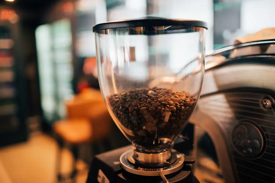 Depósito de granos de café de una cafetera automática, lleno de grano recién tostado