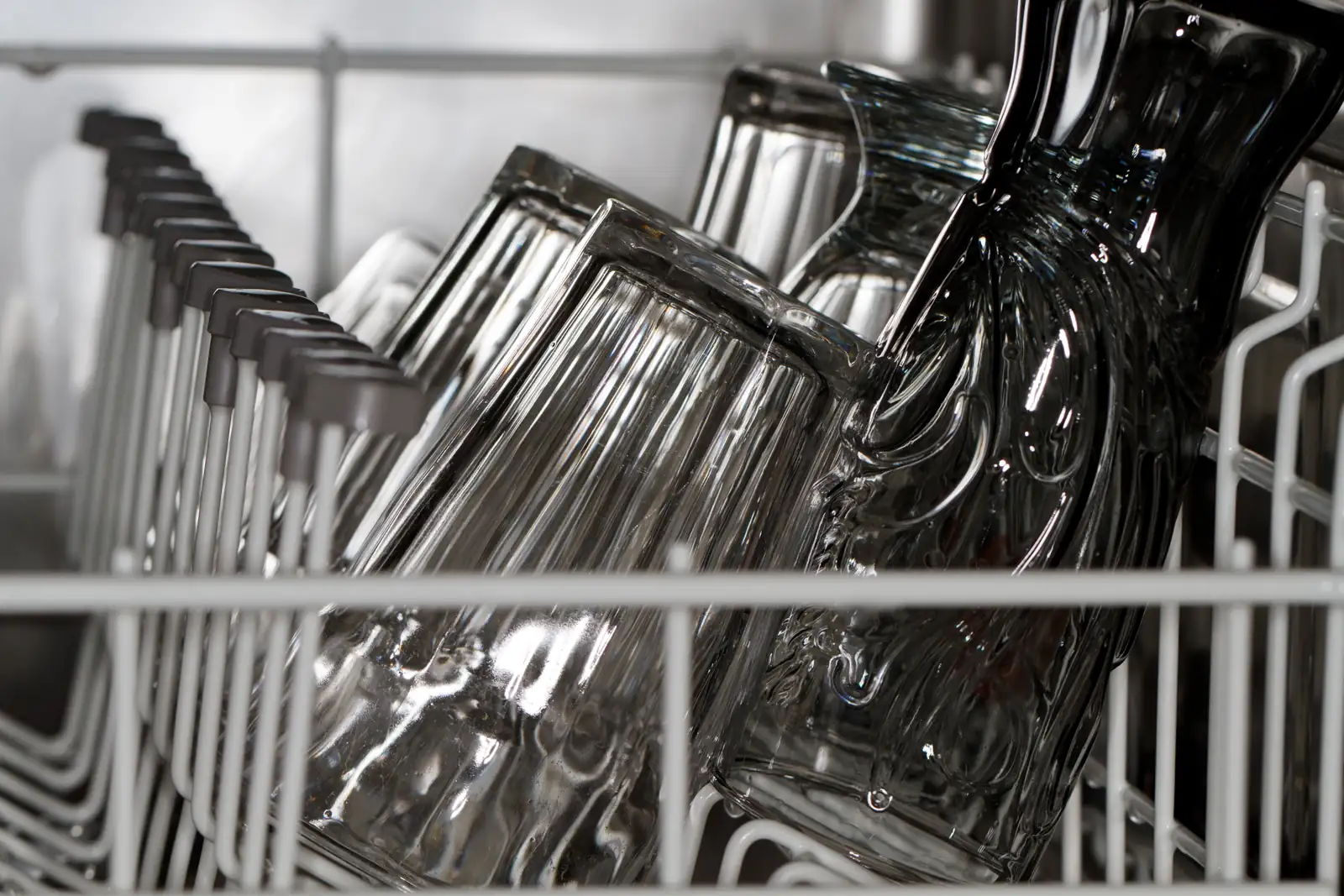 Vasos de cristal colocados boca abajo en la cesta de un lavavajillas