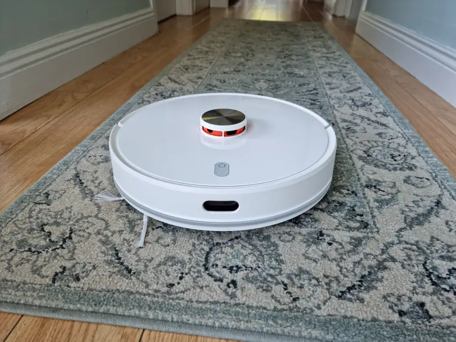 Robot aspirador con torreta de navegación láser trabajando sobre una alfombra
